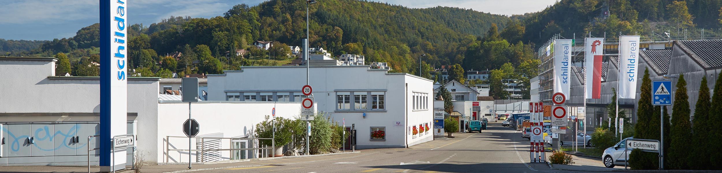 Zufahrt zum schildareal am Eichenweg mit Fahnen und bewaldetem Hang